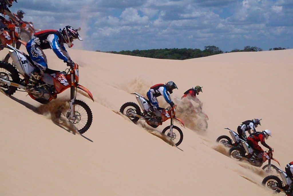 Jogo de moto de trilha empinando na areia com rampas